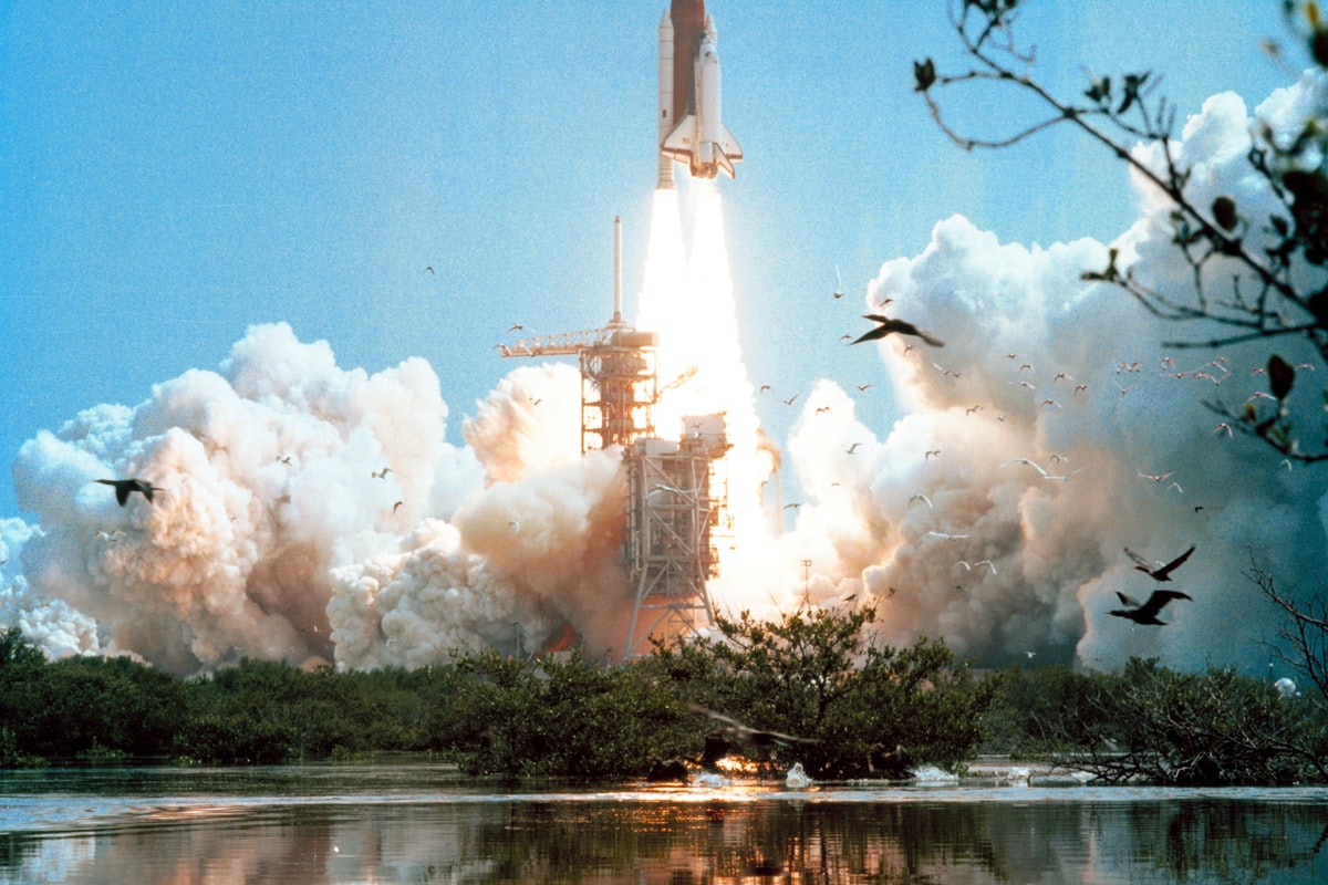 Space shuttle lifting off from the launch pad in clouds of exhaust